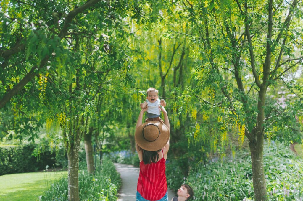 A woman lifting her baby into the air in a beautiful garden
