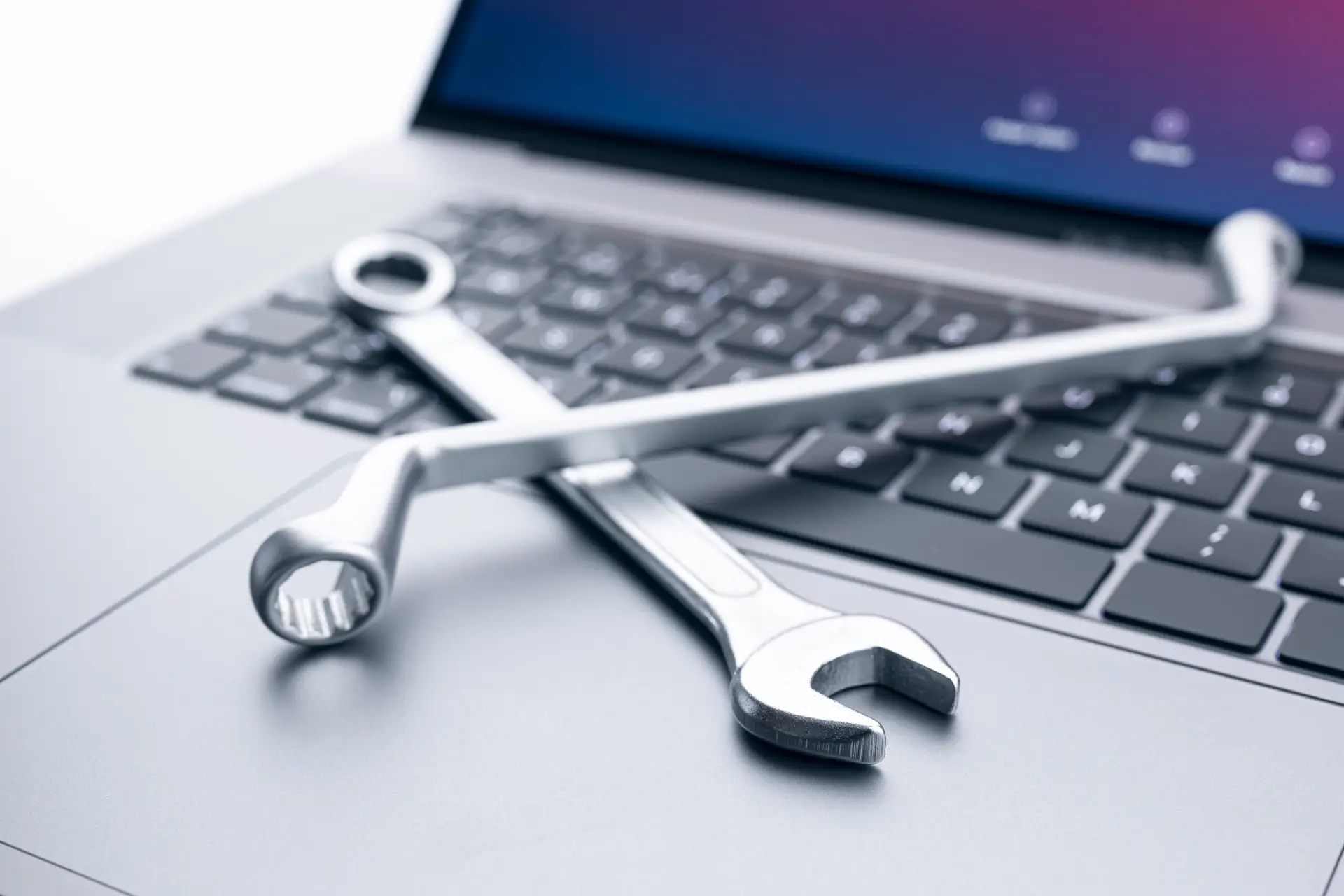 Laptop mit Schraubenschlüsseln auf der Tastatur – Symbolbild für WordPress-Wartung durch Ingenius Agency Essen