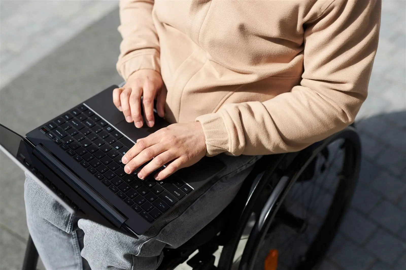 Mann im Rollstuhl arbeitet am Laptop – Symbolbild für Barrierefreiheit von Websites