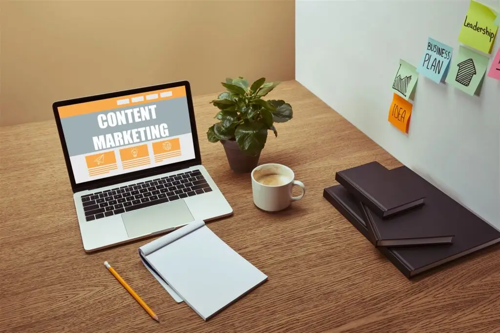 Laptop mit Schriftzug Content Marketing, Notizbücher und Stift auf Holztisch – Content Marketing Agentur Essen