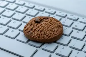 Ein Keks liegt auf einer Computertastatur – Symbolbild für den Cookie-Banner