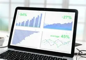 Geschäftsstatistiken auf einem Laptop-Bildschirm neben Kaffeetasse und Brille – Symbolbild für Google-Ads-Begriffe