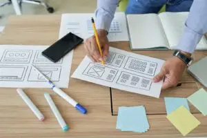 Designer plant ein Website-Layout am Schreibtisch – Symbolbild für eine Landingpage