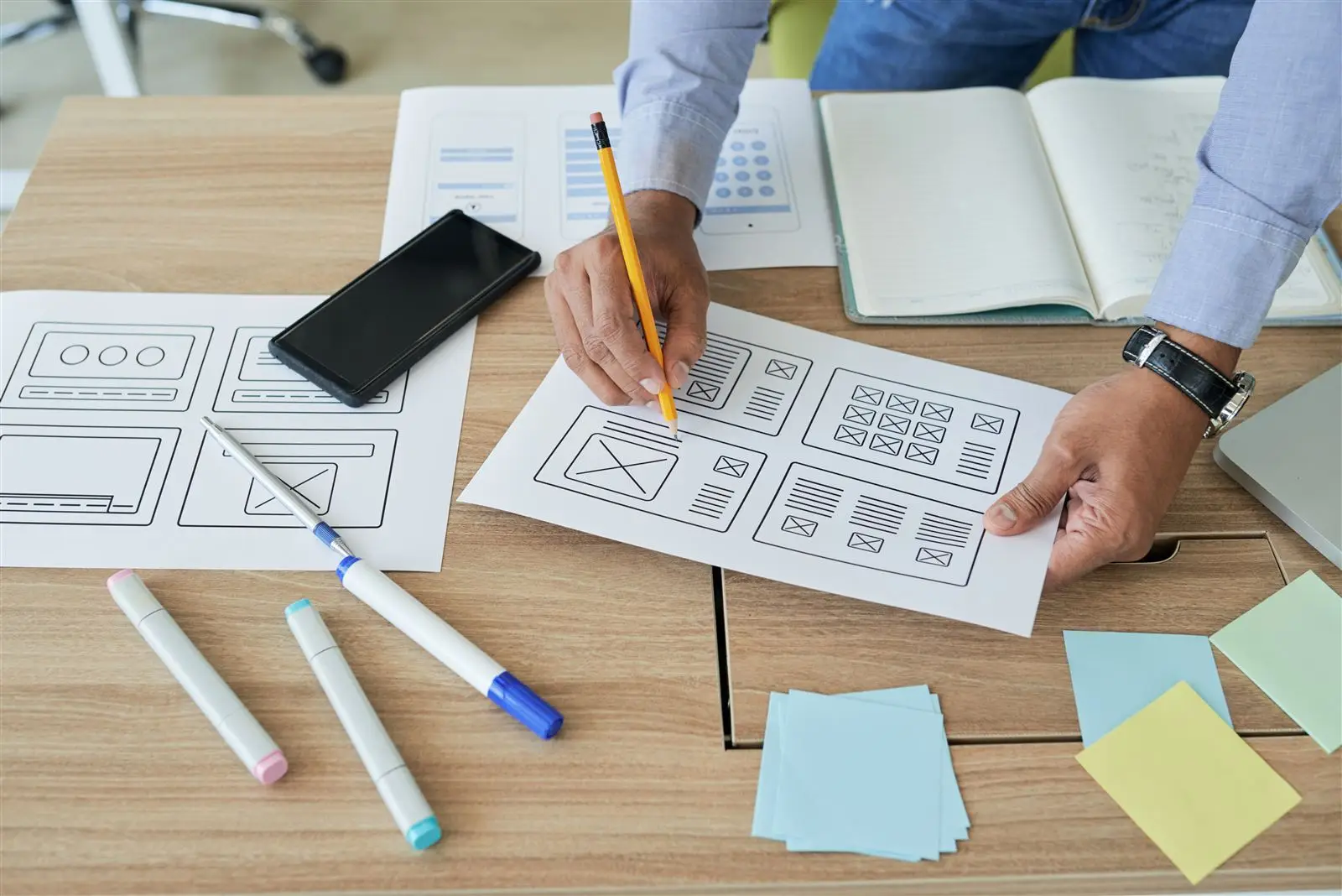 Designer plant ein Website-Layout am Schreibtisch – Symbolbild für eine Landingpage