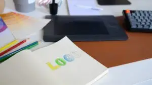 Logo-Skizze mit Farbstiften und Tablet auf dem Schreibtisch eines Designers &ndash; Symbolbild f&uuml;r Logo-Redesign