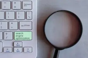 Lupe liegt auf einer Tastatur &ndash; Symbolbild f&uuml;r die Suche nach den richtigen Suchbegriffen