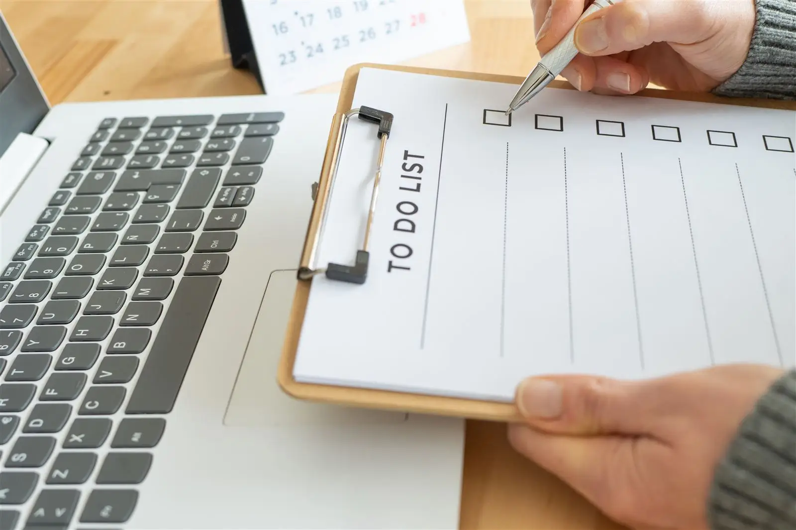 Person hakt Punkte auf einer Checkliste neben einem Laptop ab – Symbolbild für Website-Wartung als Abo